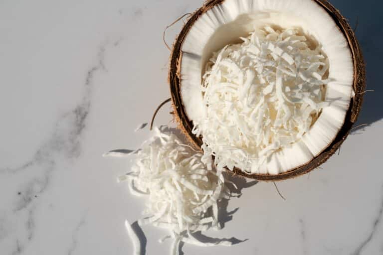 Noix de coco râpée dans un bol avec demi-noix de coco