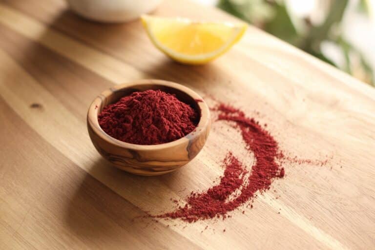 Poudre de sumac rouge dans un bol en bois d'olivier
